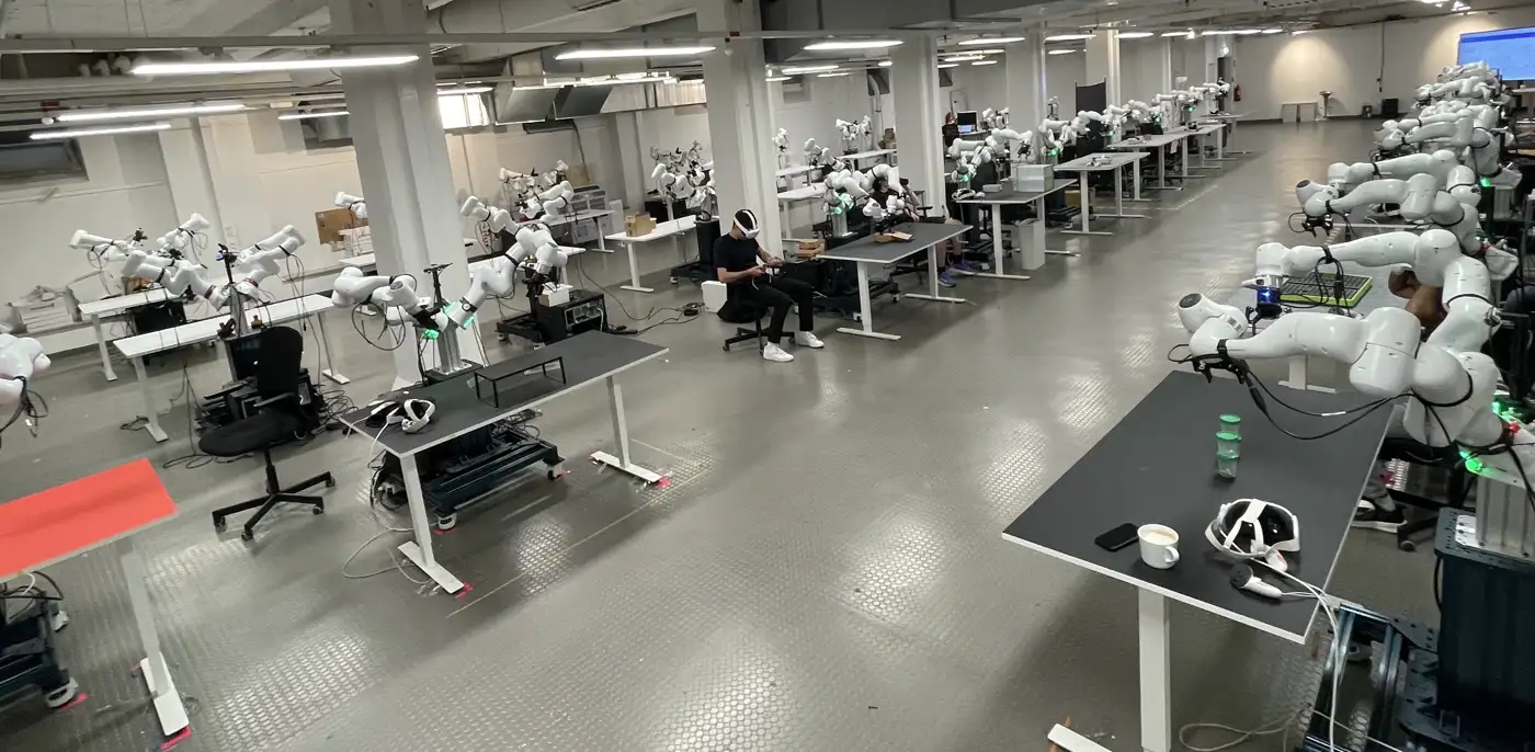 The Poke & Wiggle robot farm: the open data-collection floor, with operators in VR headsets teleoperating bimanual Franka stations.
